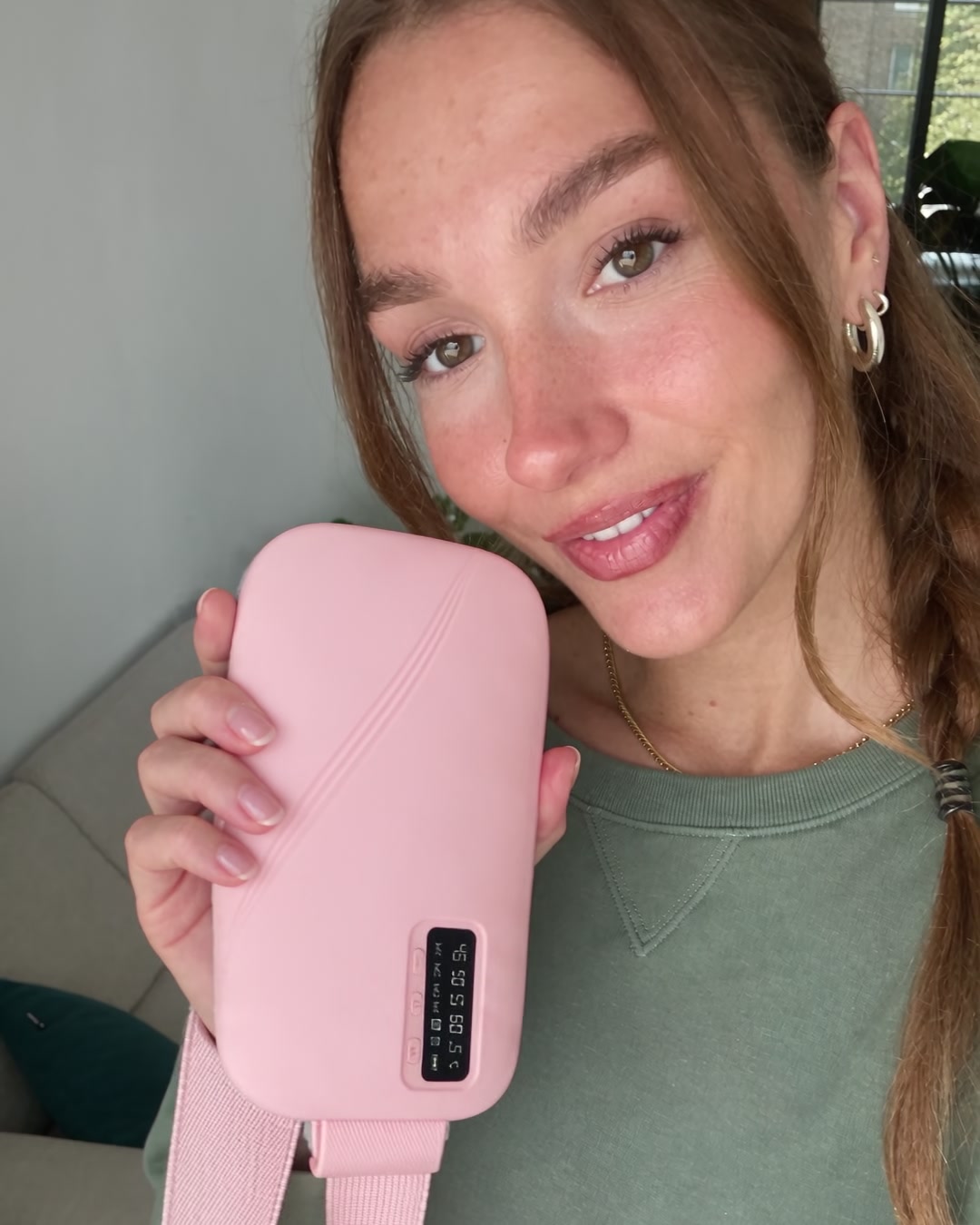 Holding up the pink Mello Soothe belt at home